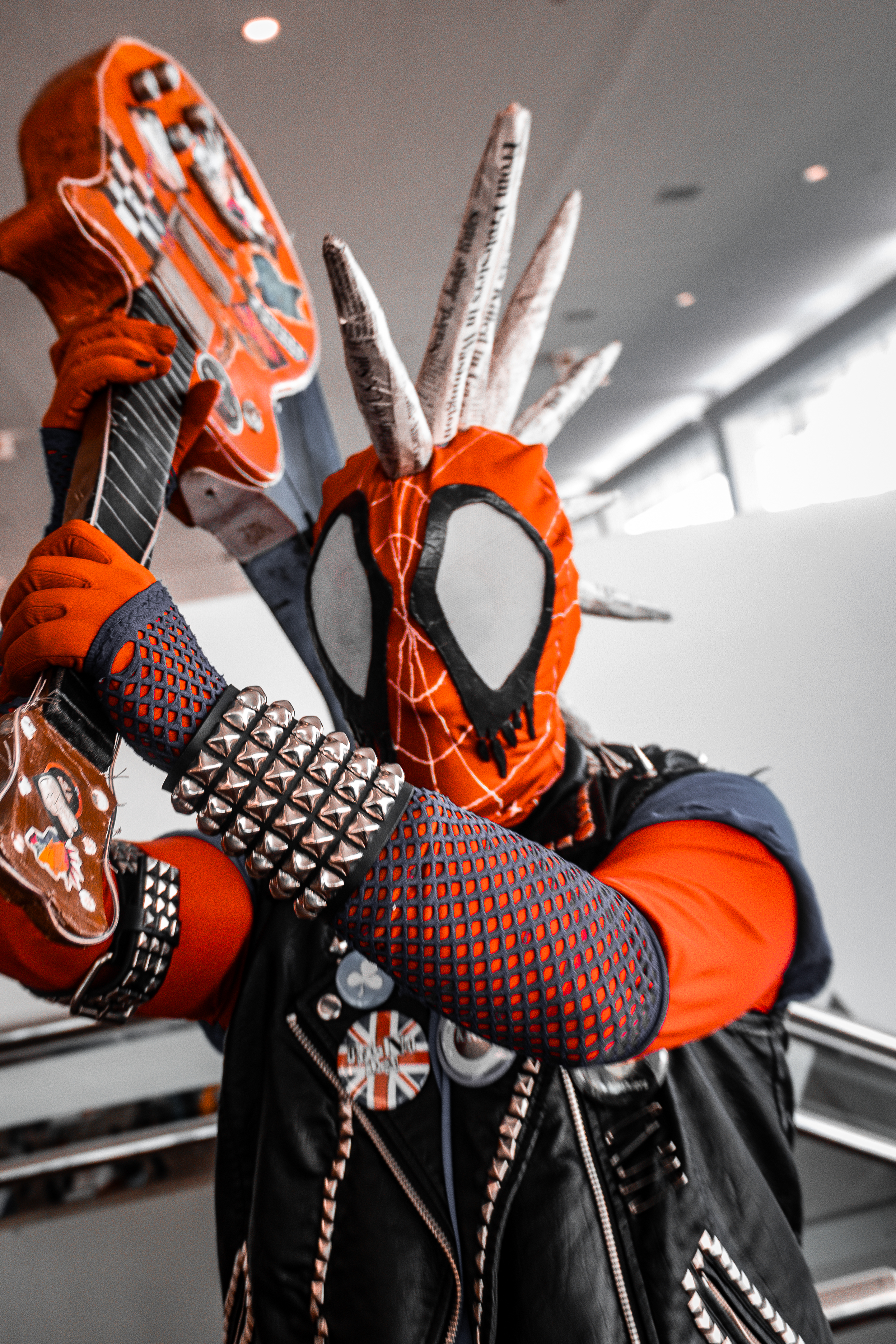 Spider-Punk cosplayer posing as if they are about to hit the camera with their guitar