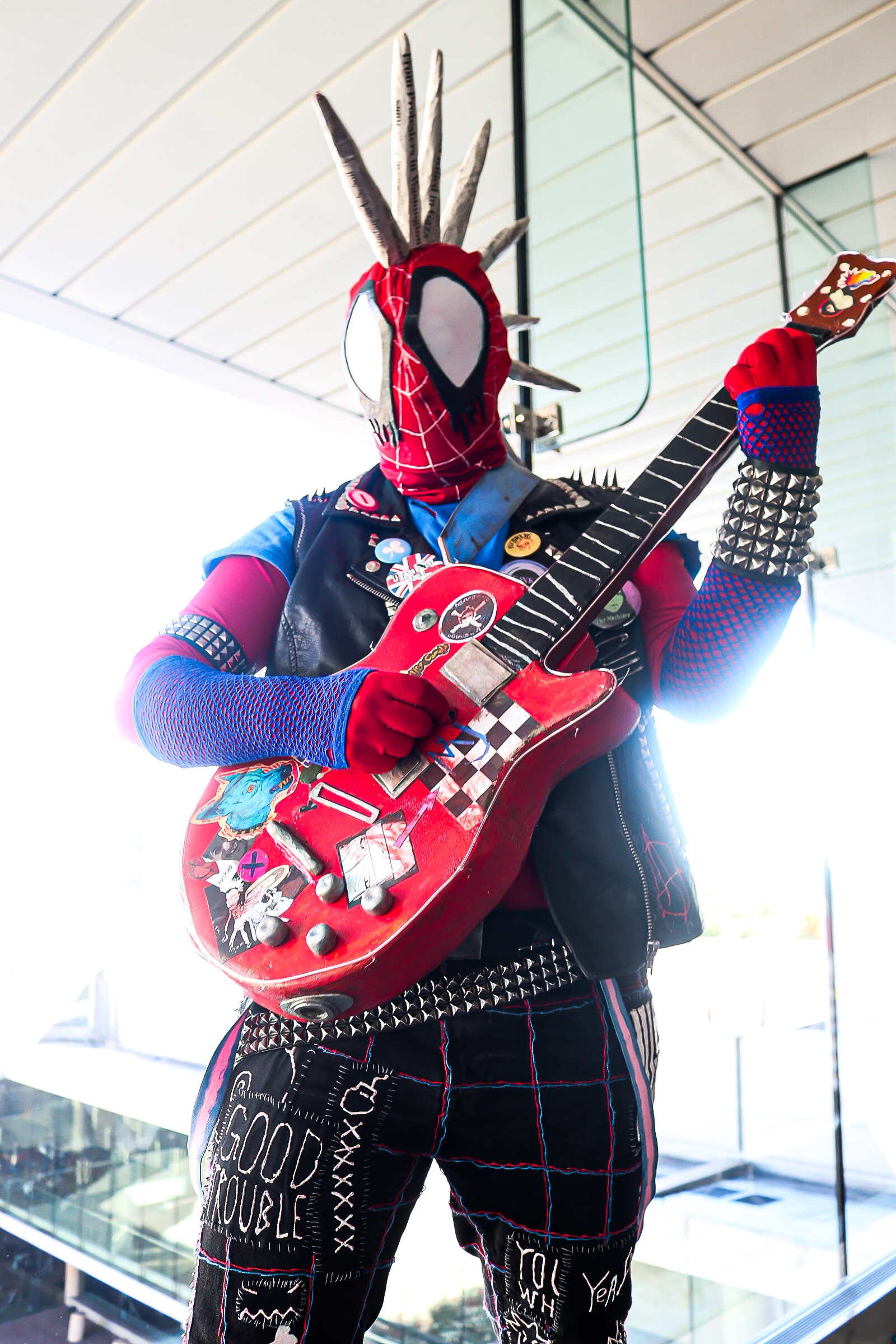 Spider-Punk cosplayer pretending to play their prop guitar