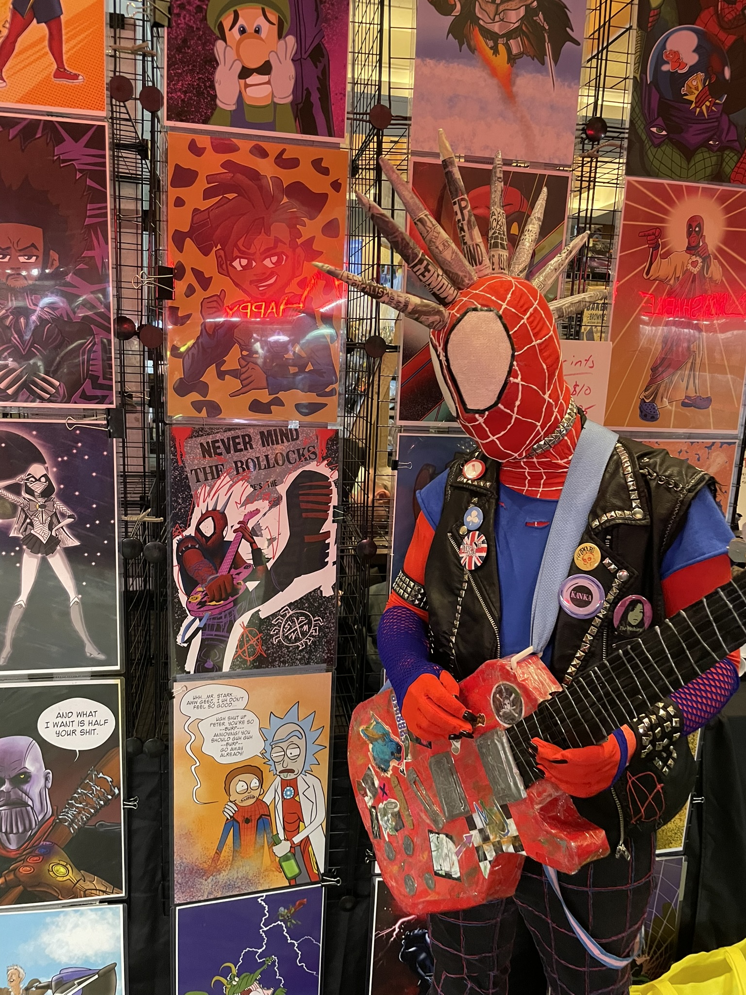 A Spider-Punk cosplayer looking at a Spider-Punk poster on a wall of posters